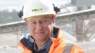 A head and shoulders picture of Mike Phillips, CEO of the British Aggregates Association, wearing orange PPE and a white hard hat, in a quarry.