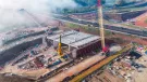 An aerial view of the A46 Kenilworth Bypass box structure under construction with a large yellow and red crawler crane and a smaller white telescopic crane and white crawler crane. Image: HS2.