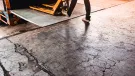 A man using a yellow trolly to unload a lorry onto a loading dock