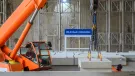 An orange crane and orange PPE-clad worker installing the first platforms at HS2's Old Oak Common station for HS2 trains.