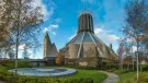 A view of Liverpool Metropolitan Cathedral in early summer with trees and a pond