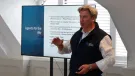 Mike Phillips, CEO British Aggregates Association, wearing a black, fleece gillet, open-necked white shirt and brown chinos, stands in front of a screen, speaking at the BAAs recent Landfill Tax consultation conference.