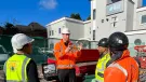 Men in a variety of PPE in front of a dental surgery discuss PERI UK and SWS's integrated waterproofing and formwork solution