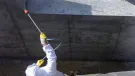 A man in white PPE Waterproofing underground sections of concrete with Vetrofluid using a low pressure pump.