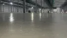 A large, newly poured concrete floor inside a large warehouse