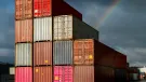 Multi-coloured containers stacked up in a yard with storm clouds and a rainbow in the background