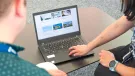 Two people look at a laptop screen which shows several photos and text related to sustainable construction