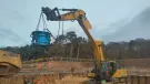 A yellow excavator lifts a blue pile cropper at the Port of Nigg, Scotland