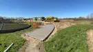 A waste water treatment plant with a CoMLaG mix access road in the foreground surrounded by grassy banks