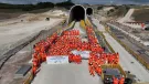A large crowd of constructions workers in orange PPE stand by the entrance to the recently completed Chiltern Tunnel, HS2’s longest, which is now structurally complete following five years of construction. 