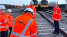 A group of people in Network Rail branded PPE inspect a concrete railway sleeper. The first-generation low-carbon concrete sleepers were installed by Concretene at GCRE in South Wales using 3.75 kg less cement per unit.