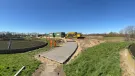 A waste water treatment plant with a CoMLaG mix access road in the foreground surrounded by grassy banks