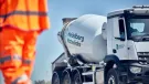 A man in orange PPE walks past a Heidelberg Materials-branded cement mixer