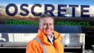 Oscrete director Scott Wilson stand in front of an Oscrete sign wearing orange PPE
