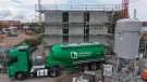 A green, Heidelberg Materials' cement truck in front of an under construction house