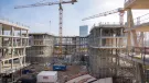 An under construction mid-rise building with two tower cranes in the background