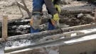 A construction worker using a trowel to help lay concrete foundations