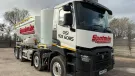 A white screed truck with red decals