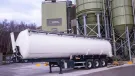 A white, material tanker standing in front of Material Evolution’s Mevo A1 Production Facility in Llay, Wrexham – the UK’s largest producer of ultra-low carbon cement, with a capacity of 120,000 tonnes per year.
