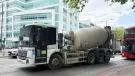 A concrete mixer drives along a street in London with a red double decker following 